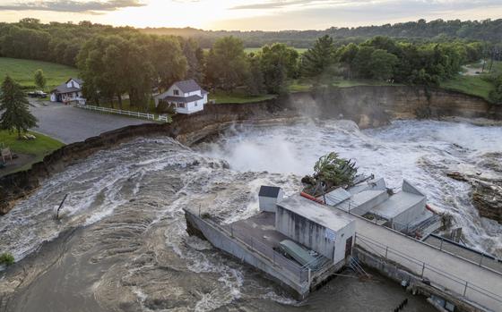 This drone photo provided by AW Aerial shows a home as it teeters before partially collapsing into the Blue Earth River at the Rapidan Dam in Rapidan, Minn., Tuesday, June 25, 2024. (Andrew Weinzierl/AW Aerial via AP)