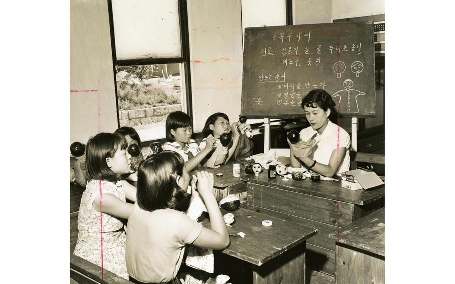 Girls paint puppets at an orphanage