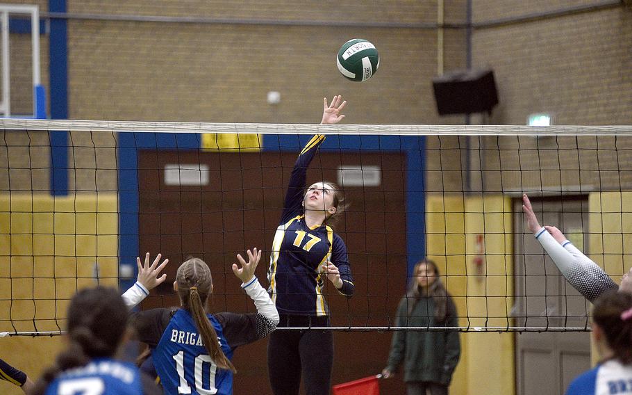 Ansbach's Trinity Batin dinks the ball at the net in a match against Brussels on Oct. 7, 2023, at AFNORTH International School in Brunssum, Netherlands. The Brigands' Grace Mamikonian, gets ready to jump for a block.