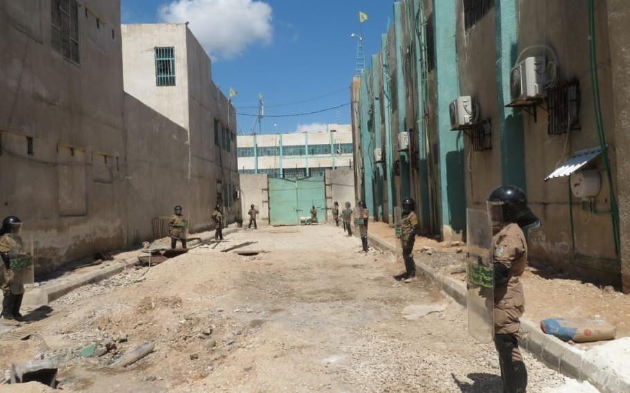 U.S.-trained prison guards stand in position with riot gear in northern Syria.