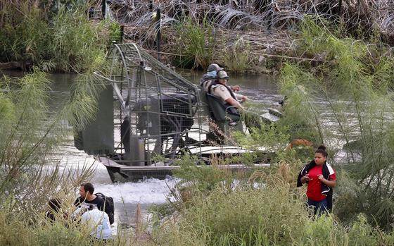 Texas Highway Patrol officers ride past migrants attempting to cross the U.S.-Mexico border along the Rio Grande in Eagle Pass, Texas on Saturday, Aug. 31, 2024.