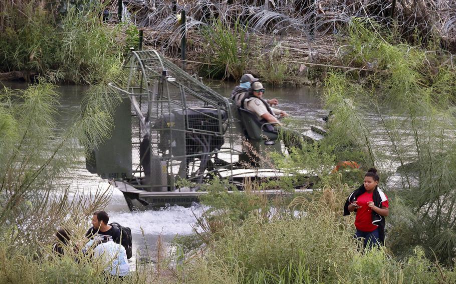 Migrants cross the Rio Grande in front of Texas Highway Patrol officers in Eagle Pass.