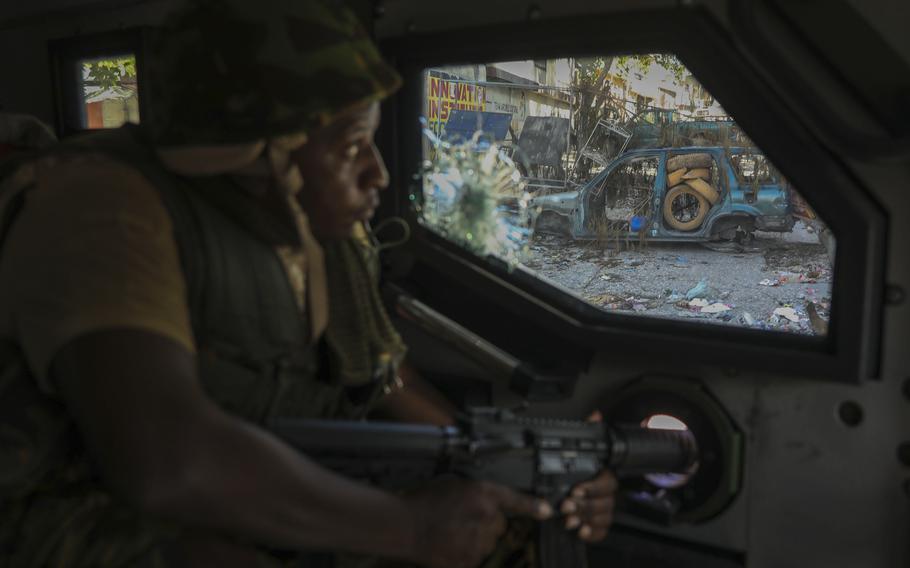 A gutted, burned-out car can be seen through the window of the vehicle of a police officer on patrol.