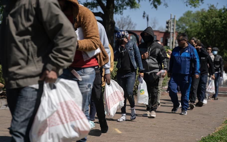 Migrants hold their belongings after arriving in D.C. on a bus from Arizona on April 18. More than 170 buses have arrived from Arizona and Texas so far, in what began as a protest in April 2022 by Republican governors over President Joe Biden's border policies.