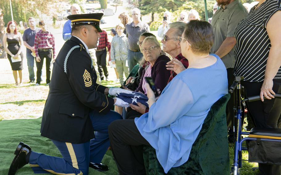 An Oregon Army National Guard Funeral Honor Guard member presents the American Flag to family members of U.S. Army Pvt. Billy E. Calkins