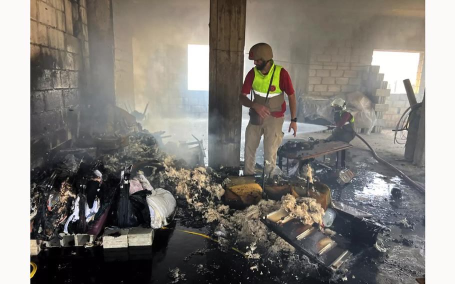 Ali Qashaqish inspects the burning remains of a furniture fire sparked by shrapnel from an Israeli strike on Aitaroun, Lebanon.