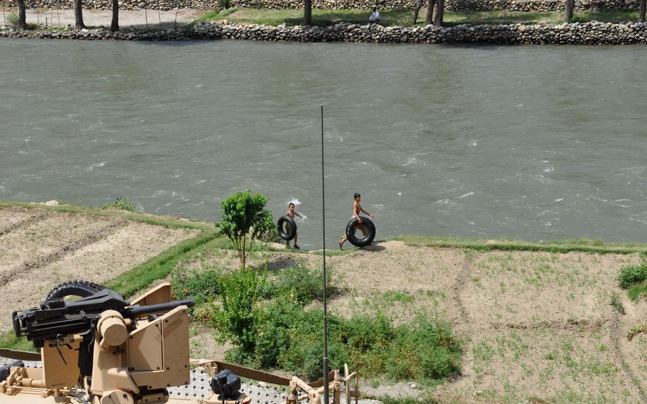 Children carry inner tubes along the Pech River despite regular fighting nearby.