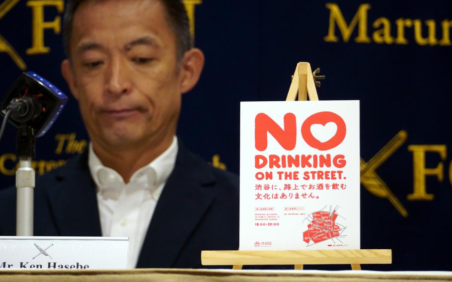 Shibuya Mayor Ken Hasebe Ken sits behind a microphone at a news conference.