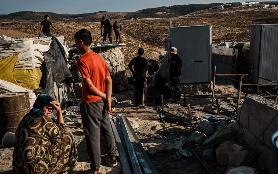 Amin Hatem, bottom left, takes in her surroundings after her family packed up their belongings to leave their homes — with another 250 Palestinians in the West Bank village of Khirbet Zanuta. The community made the decision to leave due to Israeli settler violence and harassment.