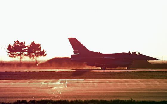  An F-16 Fighting Falcon lands on a runway flanked by two trees at Kunsan Air Base. 