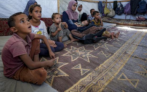 CAPTION CORRECTION: Displaced infant Abdel-Rahman Abu El-Jedian, 11-month-old, who suffers from polio, is carried by his mother, center, at a makeshift tent camp in Deir al-Balah, central Gaza Strip, Tuesday, Aug. 27, 2024. (AP Photo/Abdel Kareem Hana)