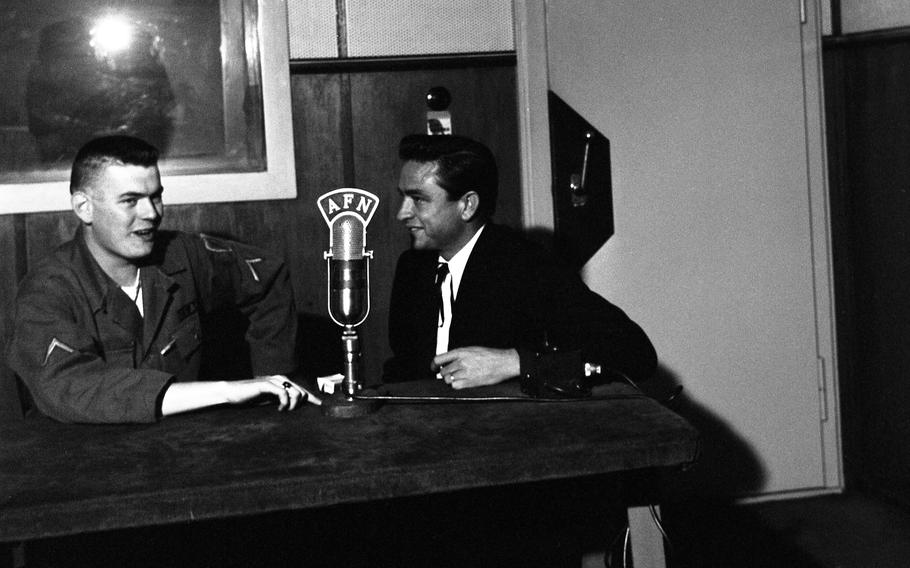 Johhny Cash, music star and Air Force veteran, visits the AFN radio studio in Frankfurt, Germany and chats with an unidentified service member. 
