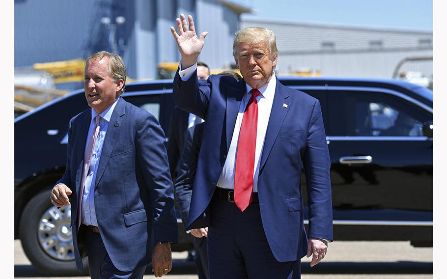 Then-President Donald Trump waves upon his arrival in Dallas, Texas, on June 11, 2020, as Texas Attorney General Ken Paxton walks alongside him.