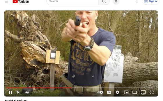 A man points a gun at the cameera during a video.