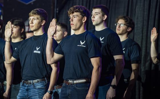 A group of recruits wearing Air Force T-shirts hold up their right hands.