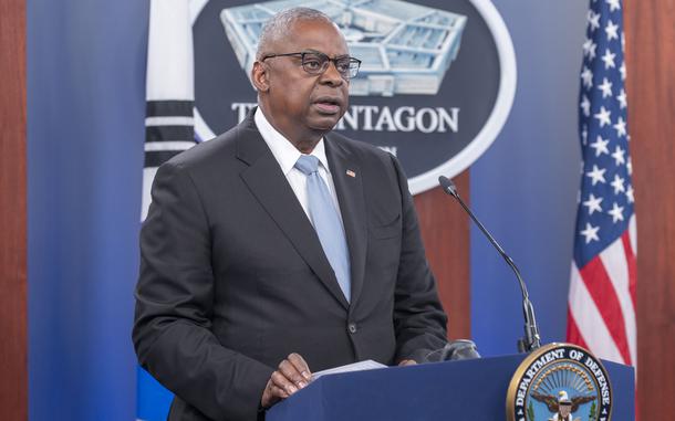 Lloyd Austin speaks while standing at a podium in front of the Pentagon emblem and a U.S. flag.