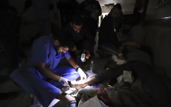 FILE - Palestinian medics treat a wounded person using torchlights after running out of power at the Indonesian hospital in Beit Lahiya during the ongoing bombardment of the northern Gaza Strip, Nov. 19, 2023. (AP Photo/Ahmed Alarini, File)