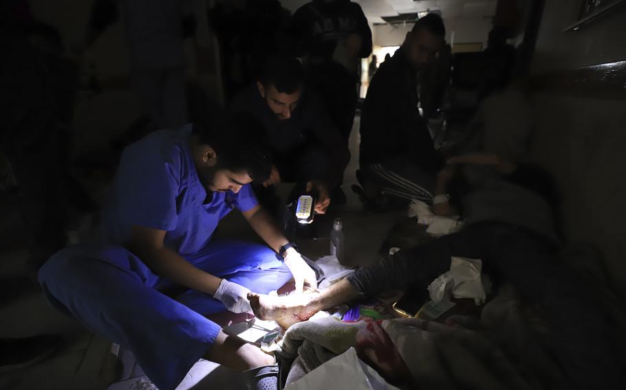 Palestinian medics treat a wounded person using torchlights after running out of power at the Indonesian hospital in Beit Lahiya during the ongoing bombardment of the northern Gaza Strip, Nov. 19, 2023.