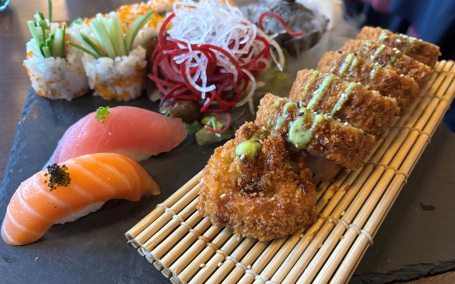 The nigiri, bottom left, spicy tuna roll, top left, and Kaiza special roll, a fried amalgamation of breaded shrimp, salmon, avocado, cucumber and cheese, arrived with the smoke of dry ice, at Kaiza in Weiden, Germany, on May 11, 2024.