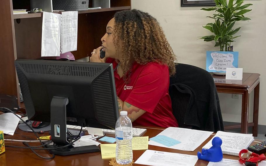 A Red Cross employee speaks on the phone while seated at her desk.