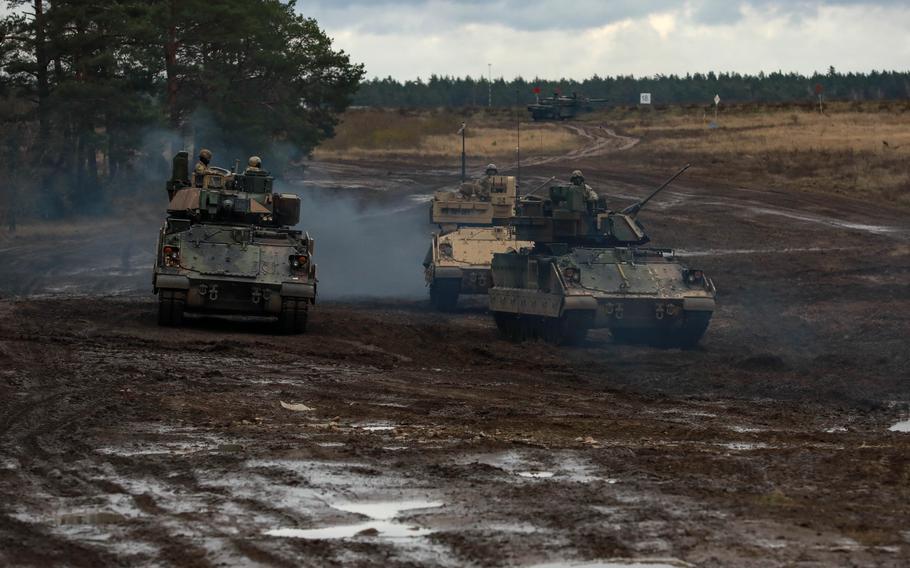 Bradley Fighting Vehicles move through a muddy field during a training excerise.