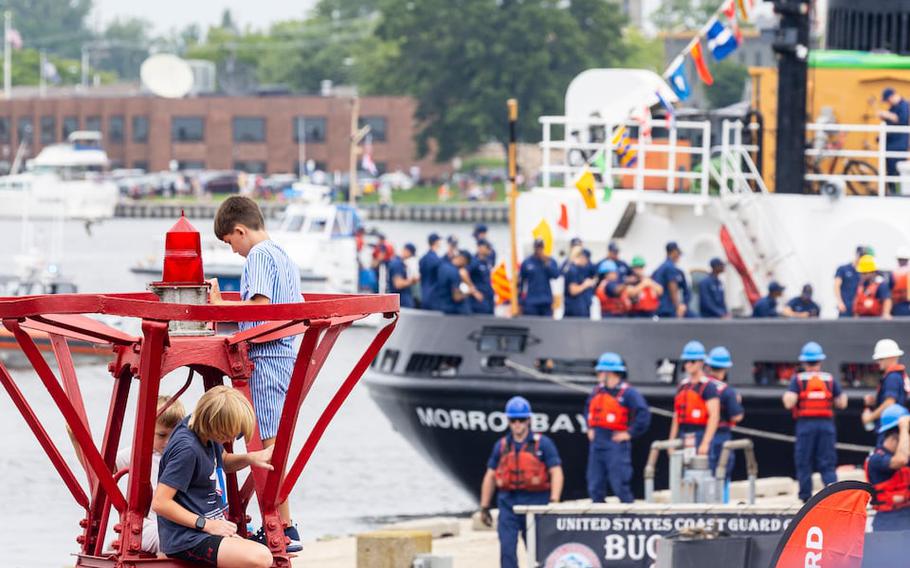 Children play in an old buoy at Escanaba Park as the USCGC Morro Bay docks during the U.S. Coast Guard parade of ships in Grand Haven, Mich., on Monday, July 29, 2024. 