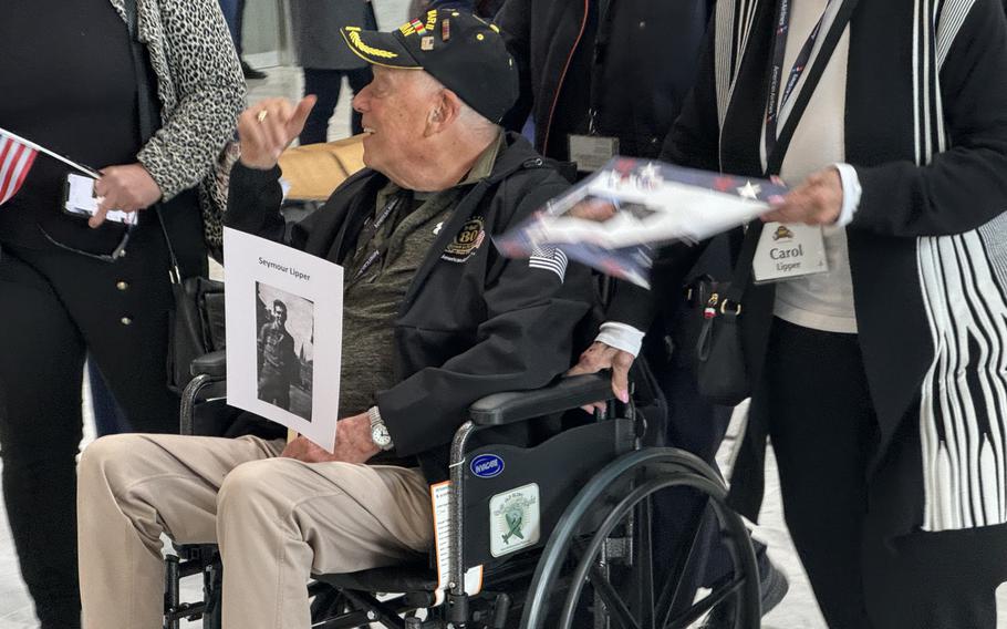 Veteran Seymour Lipper, who fought in the Battle of the Bulge in the artillery, greets well-wishers as he arrives in Paris for D-Day commemorations. 