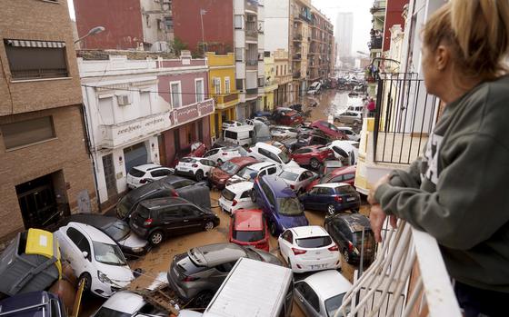 A woman looks out from her balcony as vehicles are trapped in the street during flooding in Valencia, Wednesday, Oct. 30, 2024. (AP Photo/Alberto Saiz)