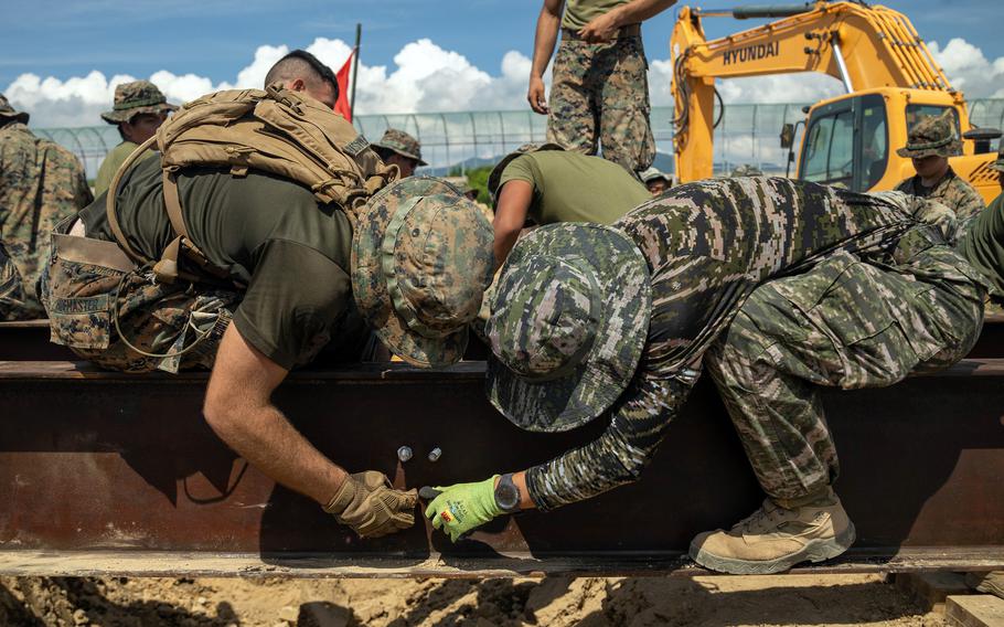 Then-Marine Corps Pfc. Michael Hofmaster, left, a combat engineer with the 9th Engineer Support Battalion, works on a bridge alongside U.S. and South Korean marines at Camp Josa-ri, South Korea, in August 2023.