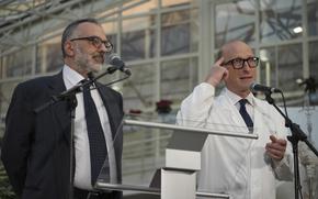 A man in a black suit and a man in a white coat seen from the waist up in front of podiums.