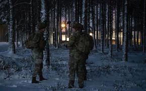 U.S. soldiers assigned to the 5th Squadron, 7th Cavalry Regiment wait under a full moon for the arrival of fellow squadron members by helicopter at a landing site near Camp Reedo, Estonia, March 14, 2025. The soldiers were involved in a reconnaissance exercise.