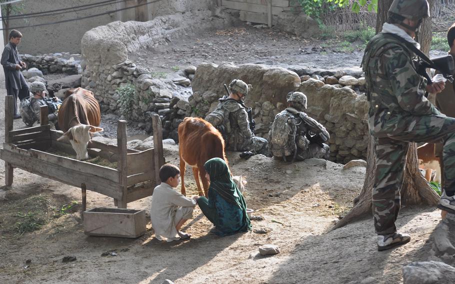 Villagers tend to animals while soldiers rest in background