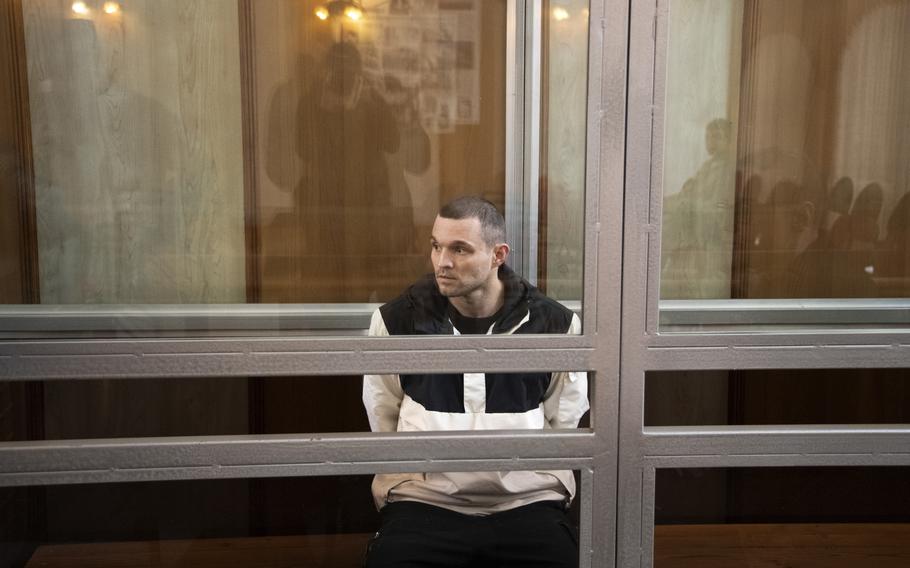 Gordon Black sits in a glass cage in courtroom.