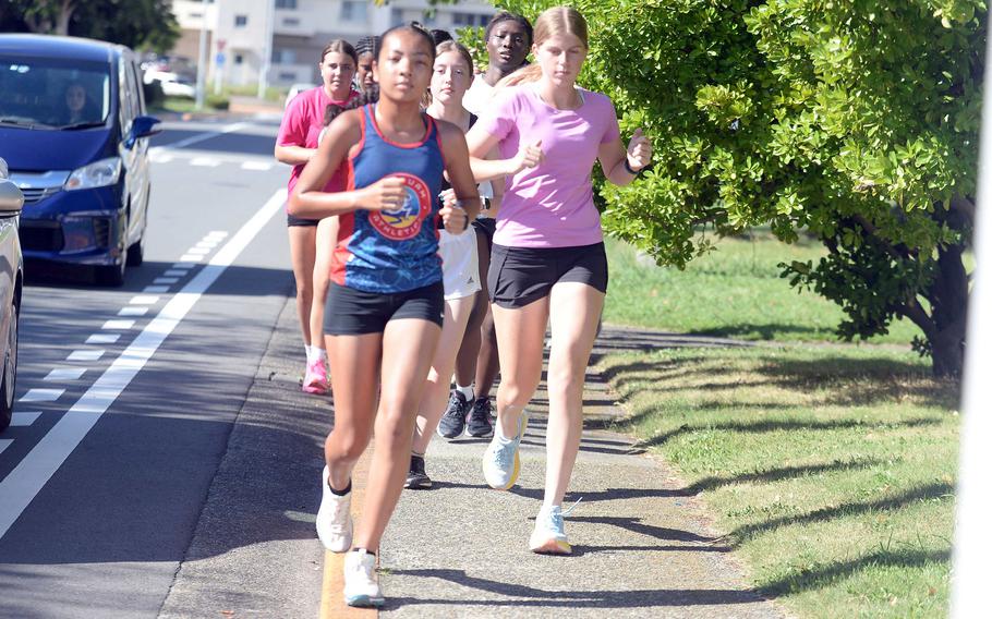 Nile C. Kinnick senior Bree Withers, right, in pink, finished second in Division I in the Far East virtual cross country meet last season and leads what coach Luke Voth calls his deepest girls team ever.