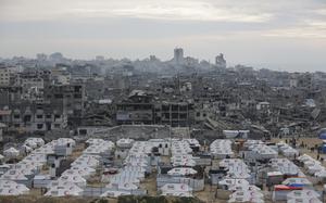 Rows of white tents in an open area, while a city of destroyed or damaged buildings stretched into the distance.