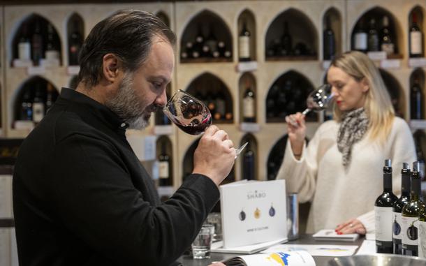 Wine Styles owner Arthur Lampros, left, and Valentyna Parsaieva, head of export for Shabo, a Ukrainian winery, right, take part in a wine tasting at Wine Styles, Dec. 20, 2024 in Dumfries, Va. (AP Photo/Kevin Wolf)