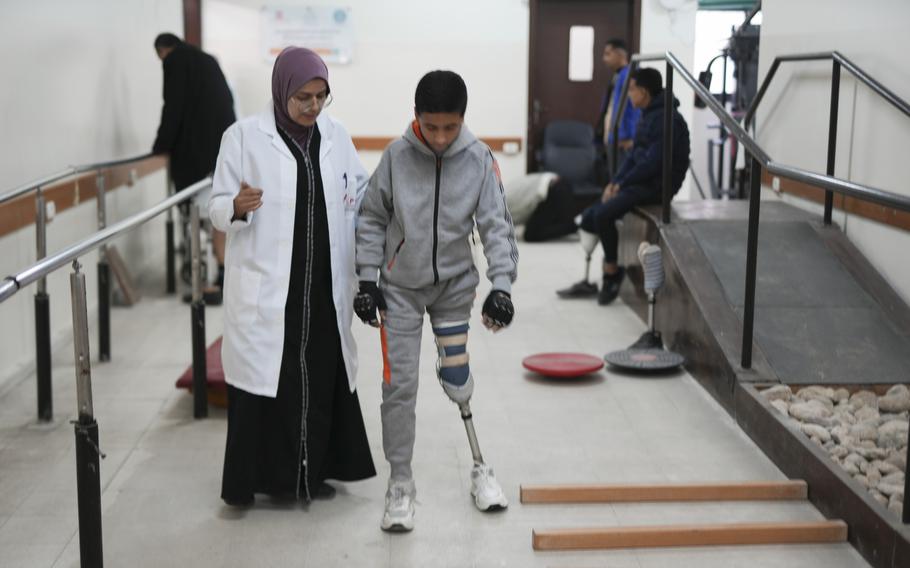 A doctor assists 13-year-old Palestinian Yamen Asfour as he learns to walk on a prosthetic leg.