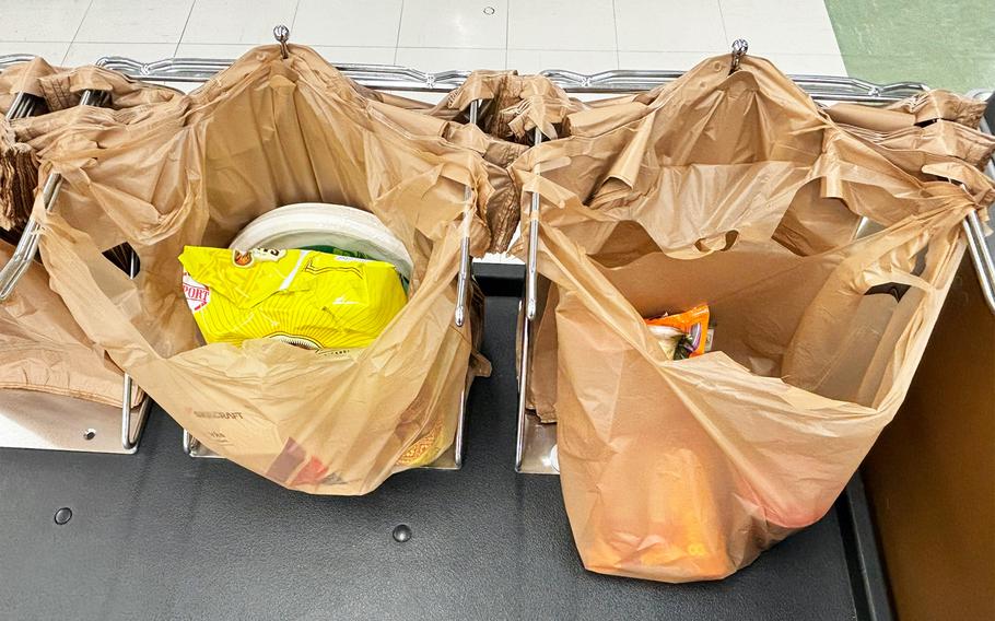 Plastic bags full of items sit on a holding rack near a commissary checkout.