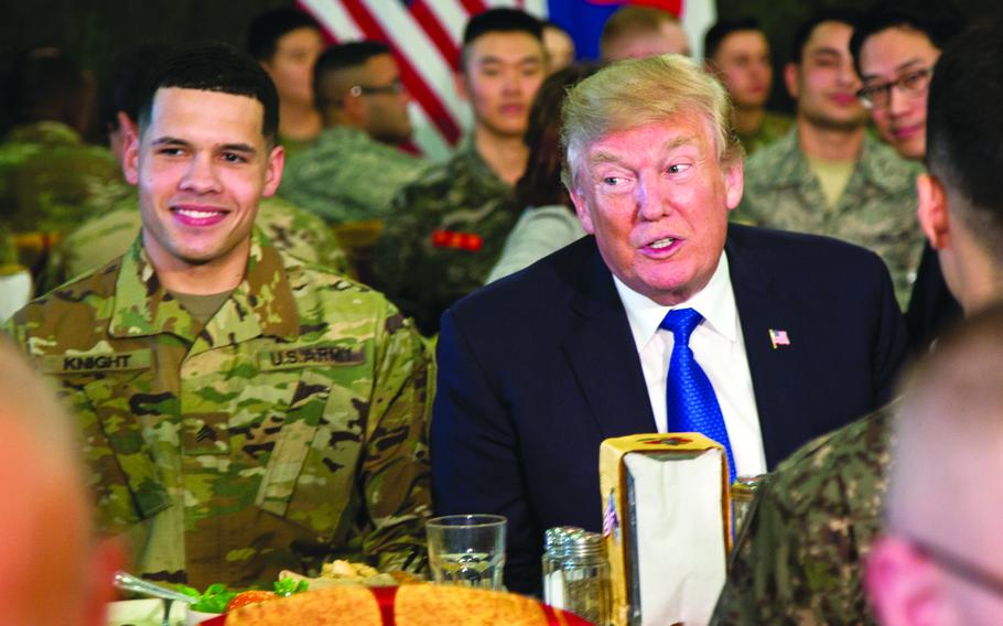 President Donald Trump sits at a lunch table with U.S. and South Korean service members.