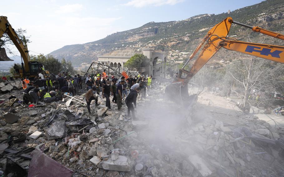 Rescue workers use excavators to remove the rubble of a destroyed house.