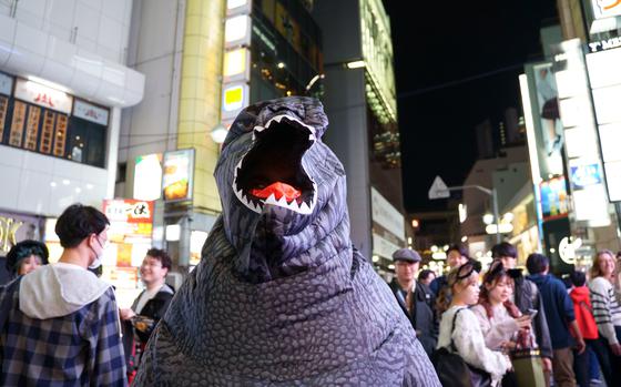 A reveler in a monster costume walks on a busy Tokyo street on Halloween.