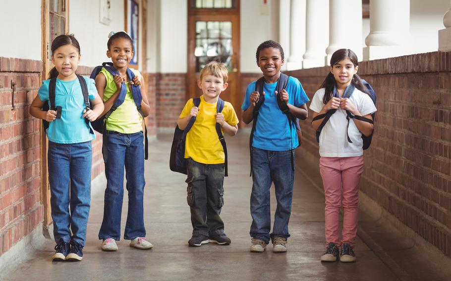 Portrait of students with schoolbags standing at corridor in school