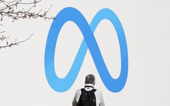 FILE - A person stands in front of a Meta sign outside of the company's headquarters in Menlo Park, Calif., March 7, 2023. (AP Photo/Jeff Chiu, File)