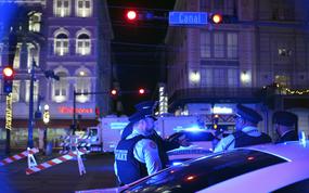 Two police officers stand near barriers under a traffic light that says, “Canal Street.”