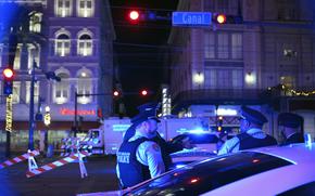 Two police officers stand near barriers under a traffic light that says, “Canal Street.”