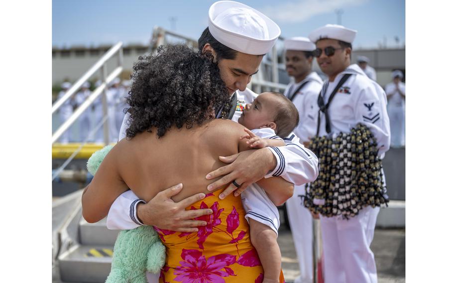 A sailor embraces his family