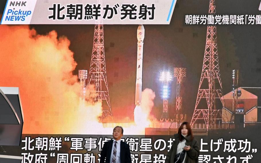 Pedestrians walk past a screen displaying the launch of North Korea's reconnaissance satellite "Malligyong-1," in the Akihabara district of Tokyo on Nov. 22, 2023.