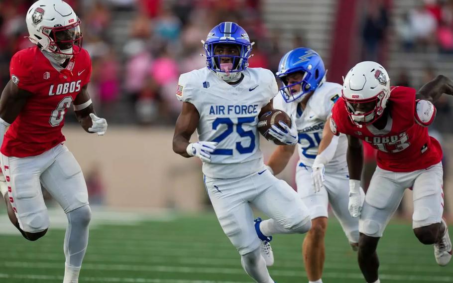 An Air Force ball carrier runs between two New Mexico defenders during a college football game.