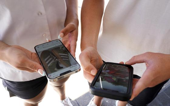 14-year-old Henry, right, and Angel, 15, use their phones to view social media in Sydney, Friday, Nov. 8, 2024. (AP Photo/Rick Rycroft)