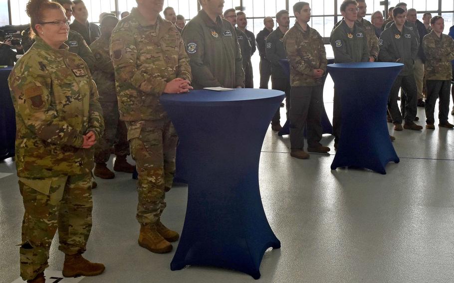 Women and men in uniform gathered at a dual bay hangar.